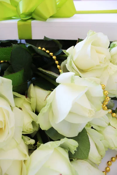 bouquet of beautiful white roses in a gift box with a light green and gold ribbon