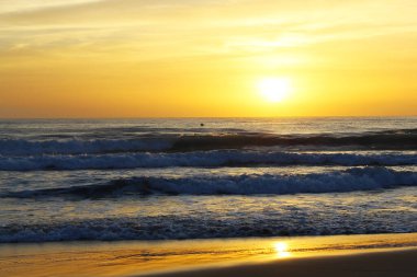 Deniz ve sahil üzerinde güneş doğuyor.