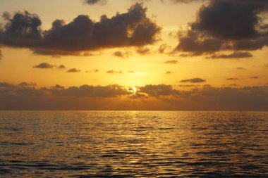 Bulutlu gökyüzünün doğal arkaplanı ve deniz üzerinde gün batımı