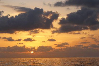 Bulutlu gökyüzünün doğal arkaplanı ve deniz üzerinde gün batımı