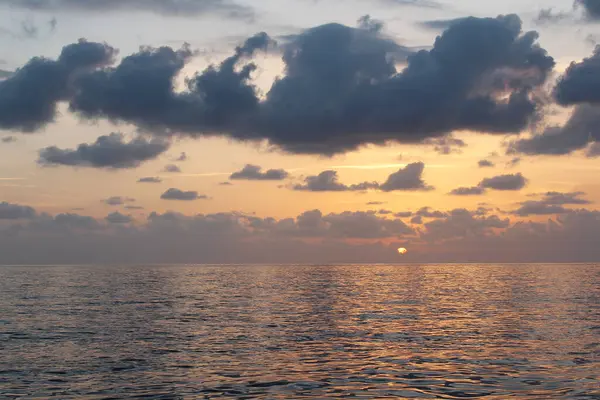 Bulutlu gökyüzünün doğal arkaplanı ve deniz üzerinde gün batımı