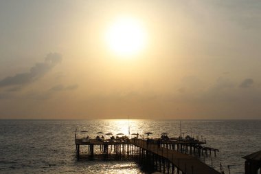 Denizin üzerinde güzel bir gün batımının arka planında bir iskele.