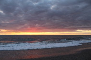 Gecenin karanlığında gün batımı denizin üzerinde bulutlu gökyüzü