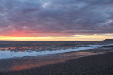 Gecenin karanlığında gün batımı denizin üzerinde bulutlu gökyüzü
