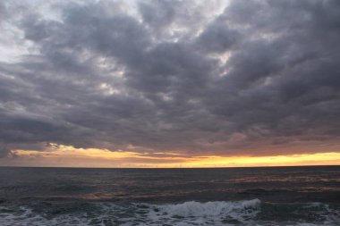 Gecenin karanlığında gün batımı denizin üzerinde bulutlu gökyüzü
