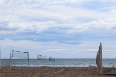 Plajda voleybol ağı, deniz üzerinde mavi gökyüzü olan kumlu sahilin güzel bir manzarası.