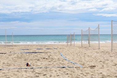 Plajda voleybol ağı, deniz üzerinde mavi gökyüzü olan kumlu sahilin güzel bir manzarası.