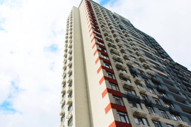 Mavi gökyüzünün arka planında pencereleri ve balkonları olan modern bina, gökyüzü olan ofis binası.