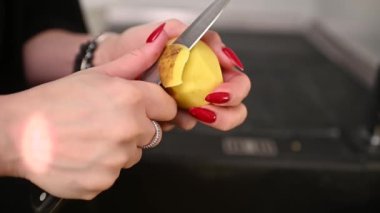 Lavaboya bıçakla patates soyan kadın. Yüksek kaliteli FullHD görüntüler