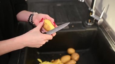 Lavaboya bıçakla patates soyan kadın. Yüksek kaliteli FullHD görüntüler