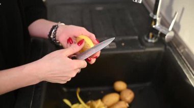 Lavaboya bıçakla patates soyan kadın. Yüksek kaliteli FullHD görüntüler