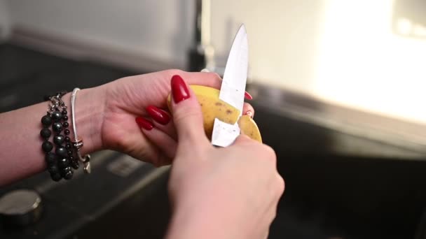 女性はシンクにナイフでジャガイモを剥がします 高品質のフルHd映像 — ストック動画