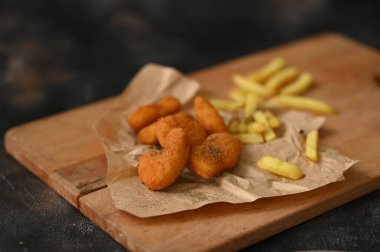 Chicken nuggets with French fries on a wooden cutting board. High quality photo clipart