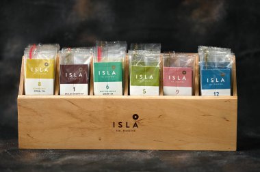 Kiev, Ukrayna - 04.01.2022. Koyu arkaplanda ahşap bir kutuda renkli çay poşetleri olan bir ada. Yüksek kalite fotoğraf