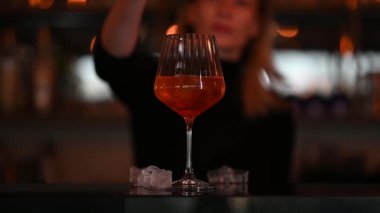 Barmen kadın şeffaf bardakta Aperol 'ün içine portakal dilimleri koyar. Yüksek kaliteli FullHD görüntüler