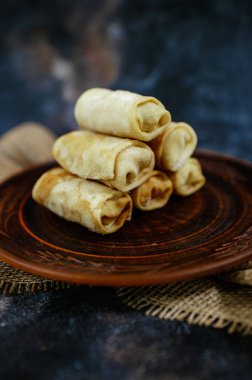 Çuval bezi desenli koyu ahşap bir tabakta altın rengi krep yığını. Yüksek kalite fotoğraf