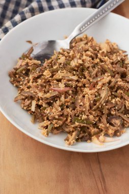 yeşil muz kabuğu kızartma tabağı, doğranmamış muz kabuğu rendelenmiş hindistancevizi ve soğanla karıştırılmış, sağlıklı yararlı fiber zengin yiyecekler gümüş kaşıkla sunuldu, seçici odak noktası fotokopi alanı.