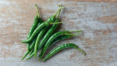 Ahşap yüzeyde yeşil biber yığını, baharatlı tatları için kullanılan yaygın sebze, doğrudan yukarıdan kopyalanmış alan ile alınır.