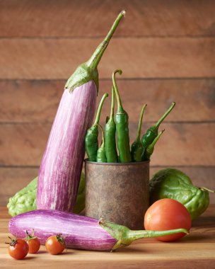 Tahta bir masanın üstünde çeşitli organik sebzeler, patlıcanların, domateslerin, yeşil biberlerin ve şiltenin yan görünüşü, fotokopi alanı olan yumuşak odaklı arka plan.