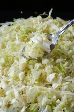 Gümüş kaşıklı doğranmış yeşil lahana yaprakları, beyaz ve soluk yeşil son derece besleyici ve lifli sebzeler pişirmeye hazır, bulanık arkaplan ile seçici odak