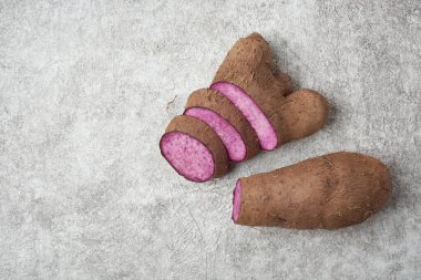 Beyaz dokulu bir yüzey üzerinde dilimlenmiş mor yer elması, dioskorea alata, diğer adıyla küp, menekşe yer elması, su veya daha büyük yer elması, mutfak ve geleneksel tıpta kullanılan mor etli yumru, kopyalama alanı