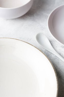 Beyaz desenli bir masanın üstünde beyaz kaşık ve bardaklı boş beyaz tabaklar, beyaz renkli ton yiyecek fotoğrafçılık arka planı, fotokopi alanı ile yumuşak odaklı.