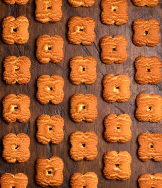 Kahverengi süt bisküvileri deseni, ahşap bir yüzeyde, atıştırmalıkların yakın görüntüsü, düz bir yiyecek arka planı.