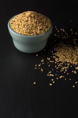Siyah yüzeydeki seramik kasede parçalanmış fasulye veya yeşil gram, moong tohumu olarak da bilinir, Güneydoğu Asya yemeklerinde temel bileşen, protein zengini baklagiller, kopyalama alanı