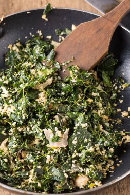 Ahşap spatulayla pişirilmiş moringa ya da baget yaprakları, rendelenmiş hindistan ceviziyle karıştırılmış ve yağla sertleştirilmiş vejetaryen sağlıklı yemek.