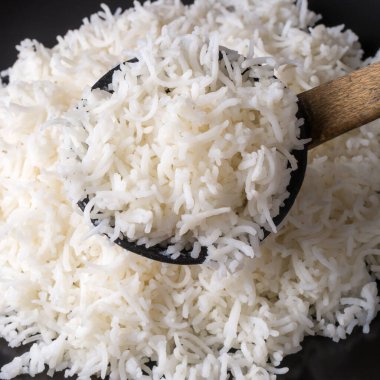 Ahşap kaşık dolusu pişmiş beyaz basmati pilavı, taze pişmiş uzun taneli aromatik pirinç, sığ bir tarlada çekilmiş, yiyecek arka planında.