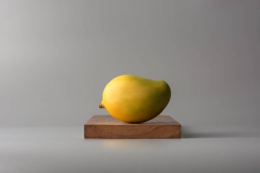 Olgun mango, tahta tepside tropikal meyve, tarafsız gri arka plan.