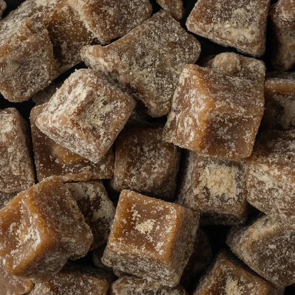 pile of jaggery pieces, golden brown colored cube shaped unrefined sugar product also called kithul jaggery or palm sugar, full frame background taken from above