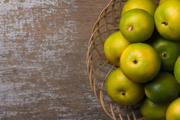 stock image sweet orange fruits in a basket, placed on rustic wooden table top, taken directly from above with space for text