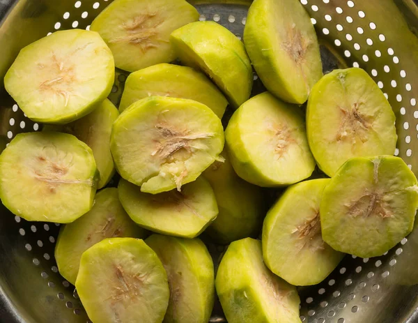 sliced ambarella or june plum, cut and peeled edible fruits in a bowl for making vegetarian condiment or sauce, close-up taken from above