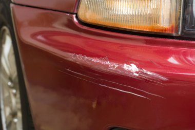 Araba gövdesi sıyrığı, yakın plan boya işi kırmızı bir araba, ulaşım ve araç servisi konseptinde kaza veya kaza sonucu soyulmuş ve hasar görmüş.