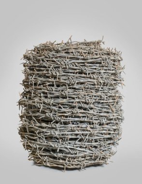 Tarafsız gri bir arkaplanda toprak izole edilmiş eski, kullanılmamış dikenli tel rulo