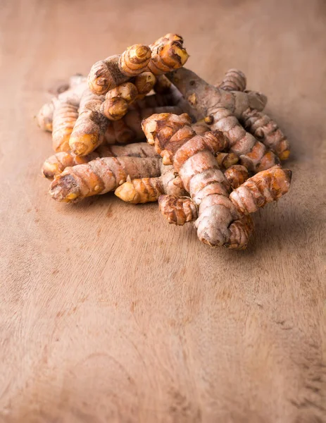 stock image turmeric roots, traditional southeast asian spice on a wooden table top, also known for medicinal purposes, taken in shallow depth of field