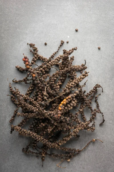 pile of dried black peppercorns, dry black pepper fruits or drupes on cement surface, spicy and seasoning ingredient, taken straight from above with copy space
