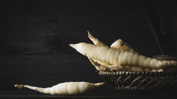 stock image close-up of organic arrowroot rhizomes in a basket, maranta arundinacea, tropical plant roots in dark moody background,soft-focus with copy space