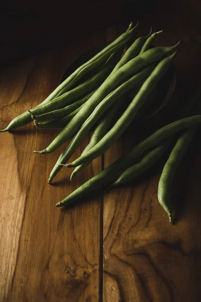 木製の表面に緑豆 フランス豆 文字列豆やスナップ コピースペースと暗いムーディーな背景で撮影した新鮮な収穫野菜としても知られています — ストック写真