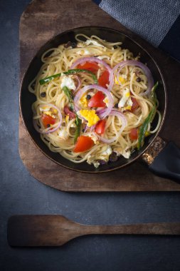 Yumurta, domates, soğan ve tavada yeşil biber ile pişirilmiş spagetti tabağı, koyu arkaplanda makarna tabağı.