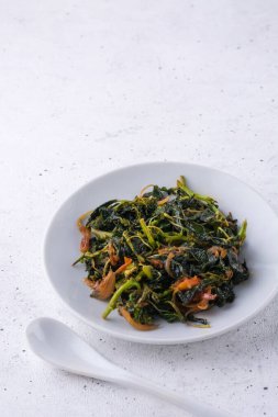 Amaranit ya da amaranth yemeği, sağlıklı yeşil yapraklı vejetaryen yemeği ve beyaz desenli bir kaşık.