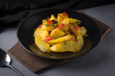 Kızarmış chayote ya da domatesli chow chow, yeşil biber ve hardal tohumları, siyah tabakta vejetaryen yemeği