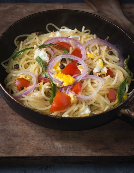 Yumurta, domates, soğan ve tavada yeşil biber ile pişirilmiş spagetti tabağı, koyu arkaplanda makarna tabağı.