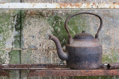 Paslı Demir Kettle paslı bir rafta eski metal arka planda oturuyor.