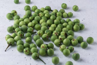 Aynı zamanda yabani patlıcan ya da bezelyeli patlıcan olarak da bilinir. Dokulu beyaz arka planda yuvarlak bir sebze.