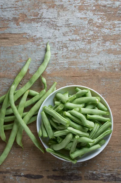 新鮮な緑の豆を白いボウルに入れ フランスの豆 文字列の豆やスナップ 素朴なテーブルの上に収穫した野菜は コピースペースで上からまっすぐ取ります — ストック写真