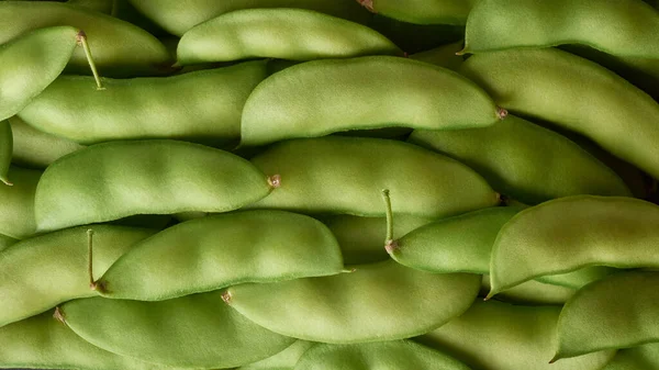 栄養価の高い種子や鞘のために広く栽培されているマメ科植物の一種であるエンドウ豆の鞘の山 フルフレームで撮影された新鮮な収穫野菜 食品の背景 コピースペースで上から撮影 — ストック写真