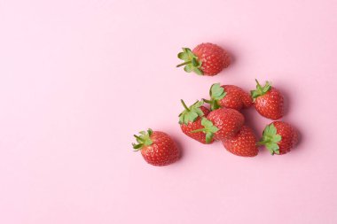 Pembe arka planda çilekler, parlak kırmızı renk tatlı bir tat ve güzel kokulu meyve, sağlıklı ve besleyici bir yemek malzemesi, yukarıdan kopyalanmış uzay ile alınmış.