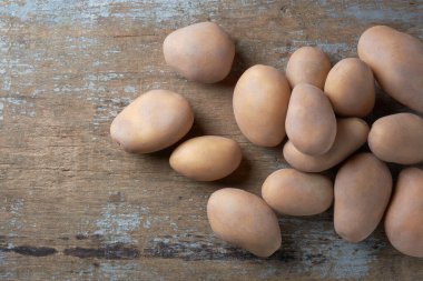 Taze toplanmış çiğ patates, solanum tüberozum, nişastalı, tüberküloz sebzeler ahşap masaya saçılmış, yukarıdan kopyalanmış